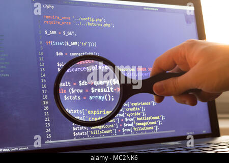 PHP back-end code zoomed through a magnifier. Computer programming source code lookup. Abstract screen of web developer. Code is created by myself. Stock Photo