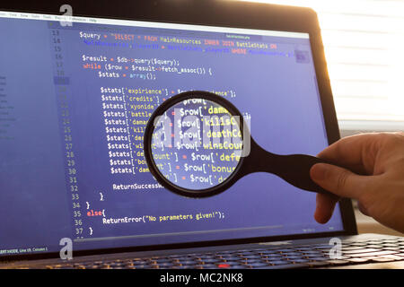 PHP back-end code zoomed through a magnifier. Computer programming source code lookup. Abstract screen of web developer. Code is created by myself. Stock Photo