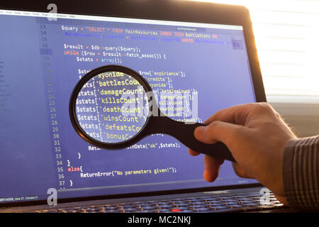 PHP back-end code zoomed through a magnifier. Computer programming source code lookup. Abstract screen of web developer. Code is created by myself. Stock Photo