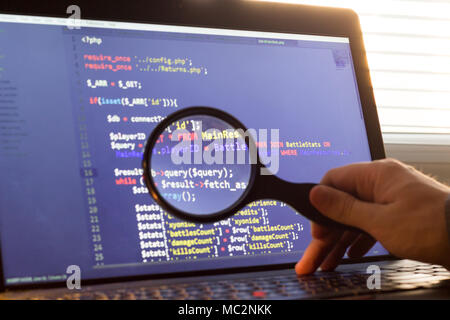 PHP back-end code zoomed through a magnifier. Computer programming source code lookup. Abstract screen of web developer. Code is created by myself. Stock Photo