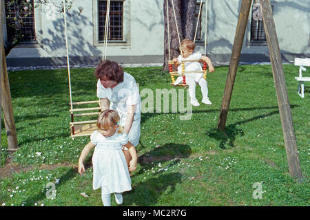 Das Kindermädchen spielt mit den beiden Töchtern Maria Theresia und Elisabeth von Thurn und Taxis im Garten von Schloss Emmeram in Regensburg, Deutschland 1983. A nanny playing with the two von Thurn and Taxis daughters Maria Theresia and Elisabeth in the garden of Emmeram castle at Regensburg, Germany 1983. Stock Photo