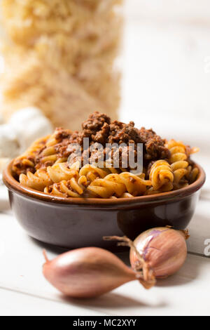 vertical closeup of traditional italian pasta with bolognese sauce with all ingredients as shallot, chese and meat  next to it, pasta is served in a t Stock Photo
