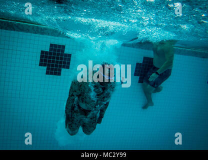 U.S. Marine Corps Pfc. Michael Prince, an infantryman with Detachment 4th Force Reconnaissance Company, jumps into the water to begin a 25 meter underwater swim during a pool training event, Marine Corps Base Hawaii, Jan. 22, 2018. The event consisted of various exercises, including static breath holds, treading exercises, a 1km swim, and gear retrievals. The unit’s training program aims to prepare students for the stresses of the BRC by offering a broad, realistic curriculum, challenging them both mentally and physically. (U.S. Marine Corps photo by Lance Cpl. Luke Kuennen) Stock Photo