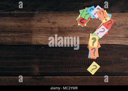 multicolored paper with QUESTION MARK on a wooden table background. questions,mystery and diversity concept. FAQ and Q&A background concept Stock Photo