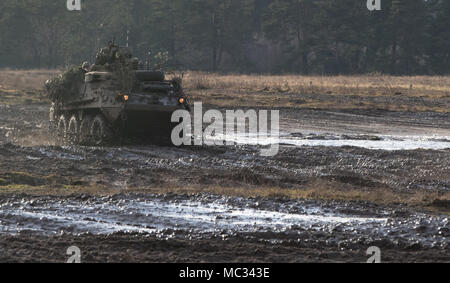 U.S. Soldiers from Kronos Troop, 3rd Squadron, 2nd Cavalry Regiment, drive their Stryker to their battle position as they participate in a mounted NATO live fire exercise coordinated by the Polish 1st Battalion 15th Mechanized Brigade at a range near the Bemowo Piskie Training Area, Poland, Jan. 30, 2018. The unique, multinational battle group, comprised of U.S., U.K., Croatian and Romanian soldiers serve with the Polish 15th Mechanized Brigade as a deterrence force in northeast Poland in support of NATO’s Enhanced Forward Presence. (U.S. Army photo by Spc. Andrew McNeil / 22nd Mobile Public A Stock Photo