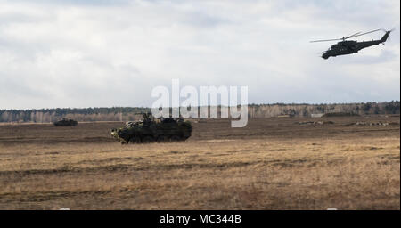 U.S. Soldiers from Kronos Troop, 3rd Squadron, 2nd Cavalry Regiment, drive their Strykers to their battle positions while a Polish MI-24 helicopter provides aerial support as they participate in a NATO live fire exercise coordinated by the Polish 1st Battalion 15th Mechanized Brigade at a range near the Bemowo Piskie Training Area, Poland, Jan. 30, 2018. The unique, multinational battle group, comprised of U.S., U.K., Croatian and Romanian soldiers serve with the Polish 15th Mechanized Brigade as a deterrence force in northeast Poland in support of NATO’s Enhanced Forward Presence. (U.S. Army  Stock Photo