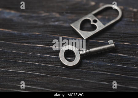 Vintage bronze lock and key on a wooden table. Close-up view Stock Photo