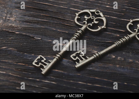 Two vintage bronze keys on a wooden table. Close-up view Stock Photo