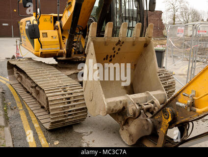 JCB JS220 tracked excavator and digging bucket on double yellow lines next to demolition site in bury lancashire uk Stock Photo