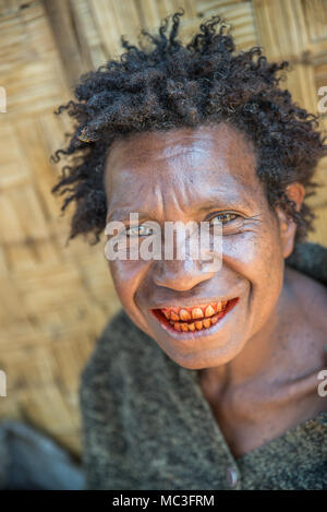 A Papuan woman with reddish teeth caused by betel nut chewing, Eastern Highlands Province, Papua New Guinea Stock Photo