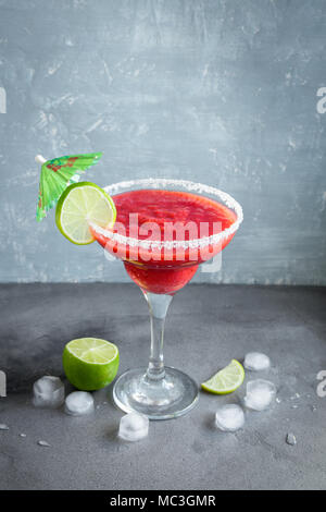 Strawberry Margarita Сocktail with lime on grey stone table, copy space. Frozen Margarita or Daiquiry Cocktail. Stock Photo