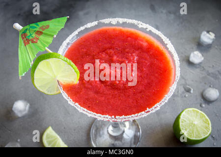 Strawberry Margarita Сocktail with lime on grey stone table, copy space. Frozen Margarita or Daiquiry Cocktail. Stock Photo