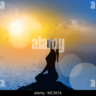 Yoga silhouette on the beach in sunrays. The dawn sun. Stock Photo