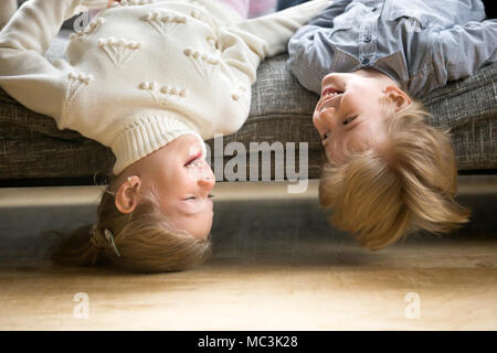 Happy boy and girl having fun together lying upside down  Stock Photo