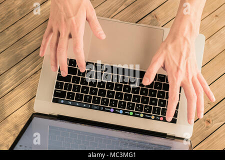 Male hands on the keyboard. Up view of male hands typing on the MacBook keyboard. Stock Photo