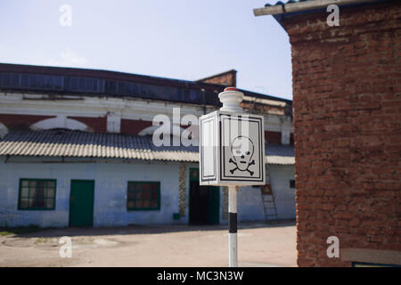 Danger sign with skull and cross bones at abandoned old rusty soviet railway station. Horizontal color photography. Stock Photo