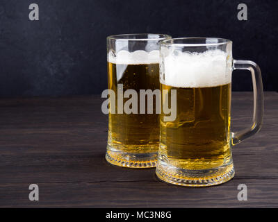 Two tall elegant pint glasses of cold wheat beer with a frothy head on a  wooden bar table conceptual of Oktoberfest Stock Photo - Alamy