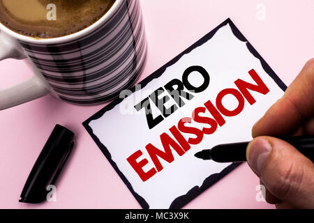 Handwriting text writing Zero Emission. Concept meaning Engine Motor Energy Source that emits no waste products written by Man on Sticky Note paper holding Marker plain background Coffee Cup Stock Photo