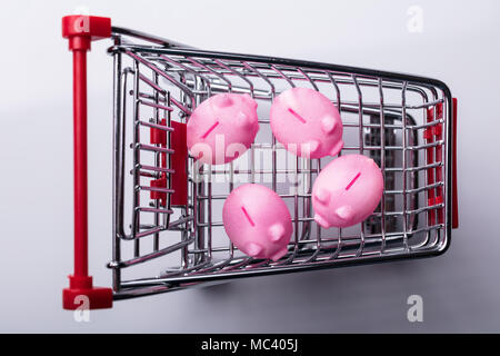 Elevated View Of Shopping Cart With Pink Piggy Banks Stock Photo