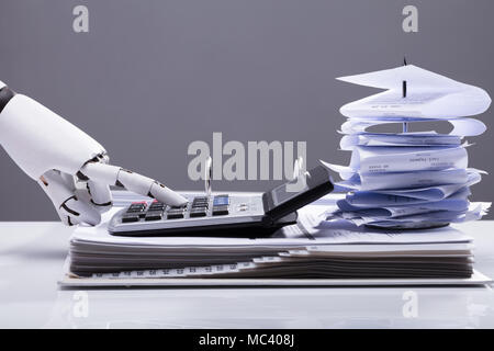 Close-up Of A Robotic Hand Calculating Bills Using Calculator In Office Stock Photo