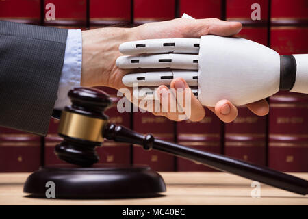 Robot Shaking Hands With Judge Near Gavel On Wooden Desk Stock Photo
