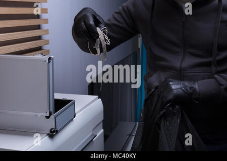 Close-up Of A Robber's Hand Wearing Gloves Stealing Jewelry From Box Stock Photo