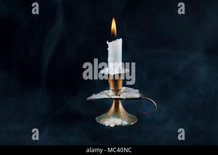 Candle in old candlestick and smoke in background isolated on dark background Stock Photo