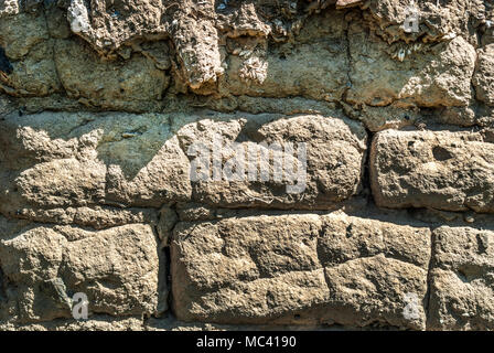 Earthen bricks wall texture on primitive old house on daylight outside, close up Stock Photo