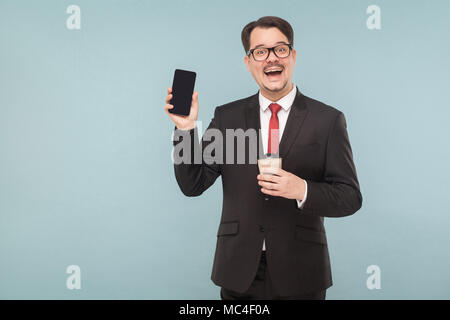 Business, gadgets,technologies. Man showing new phone. Indoor, studio shot, isolated on light blue or gray background Stock Photo