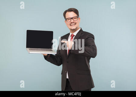 Business, gadgets,technologies. Businessman pointing in monitor laptop. Indoor, studio shot, isolated on light blue or gray background Stock Photo