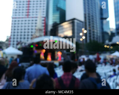 Defocused scene of crowd of people attending public concert celebrating New Year festival in city in Evening Stock Photo