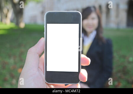 A hand holding smart phone to take photo of unidentified corporate lady in a park Stock Photo