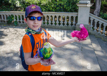 A young boy holds two dyed fantail pigeons on a holiday in Barcelona, Spain. Stock Photo