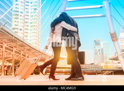 Happy couple hugging in love in the street after a travel in a colorful scenery Stock Photo