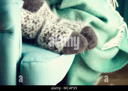 Feet in woolen socks. Cozy autumn evening. Winter and Christmas holidays concept. Copy space