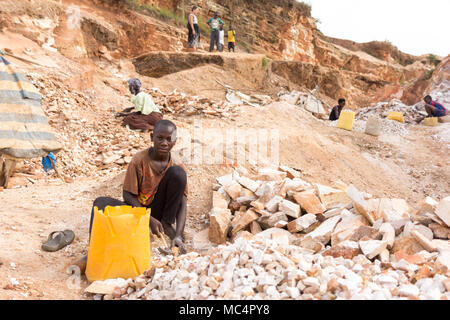 Lugazi, Uganda. June 18 2017. A Ugandan boy breaking rocks into small slabs for his foreman. Basically child labour. Stock Photo