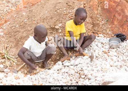 Lugazi, Uganda. June 18 2017. Ugandan boys breaking rocks into small slabs for sale to their foreman. Basically child labour. Stock Photo