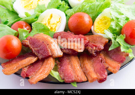 Fragment dish closeup with shredded lettuce, cherry tomatoes, bacon and boiled eggs with shallow depth of field Stock Photo