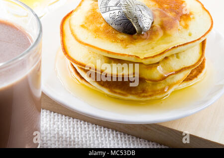 Glass mug of hot cocoa and pancakes with honey close-up with shallow depth of field Stock Photo