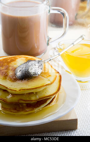 Pancakes with honey and a cup of hot cocoa on a table for lunch for one person with a shallow depth of field Stock Photo