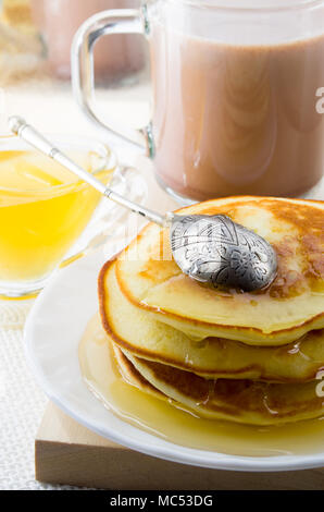 Pancakes with honey and mug of hot cocoa on a table for lunch for one person with a shallow depth of field Stock Photo