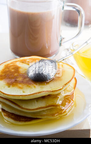 Pancakes with honey and a cup of hot cocoa on a table for lunch for one person with a shallow depth of field Stock Photo