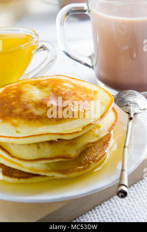 Mug with cocoa, honey and pancakes for dessert closeup with shallow depth of field. Stock Photo