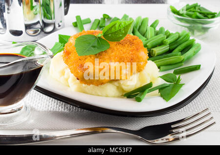 Close-up view of fried chicken, mashed potatoes and green beans with leek Stock Photo