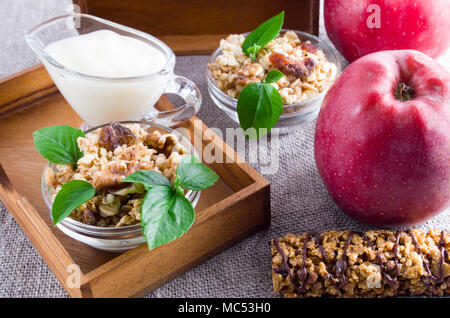 Useful products for breakfast. Muesli with nuts and raisins, apples and yogurt on a gray tablecloth closeup Stock Photo