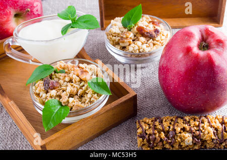 Healthy foods for breakfast. Oat cereal with nuts and raisins, apples and yogurt on a gray tablecloth closeup Stock Photo