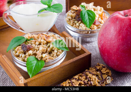 Healthy ingredients for breakfast. Oat cereal with nuts and raisins, apples and yogurt on a gray tablecloth closeup Stock Photo