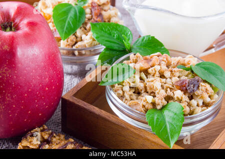 Healthy ingredients for breakfast. Oat cereal with nuts and raisins, apples and yogurt on a gray tablecloth closeup Stock Photo