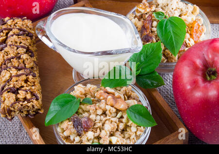 Healthy ingredients for breakfast. Oat cereal with nuts and raisins, apples and yogurt on a gray tablecloth closeup Stock Photo