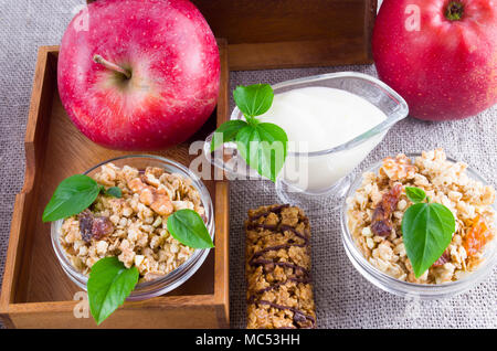 Healthy ingredients for breakfast. Oat cereal with nuts and raisins, apples and yogurt on a gray tablecloth closeup Stock Photo